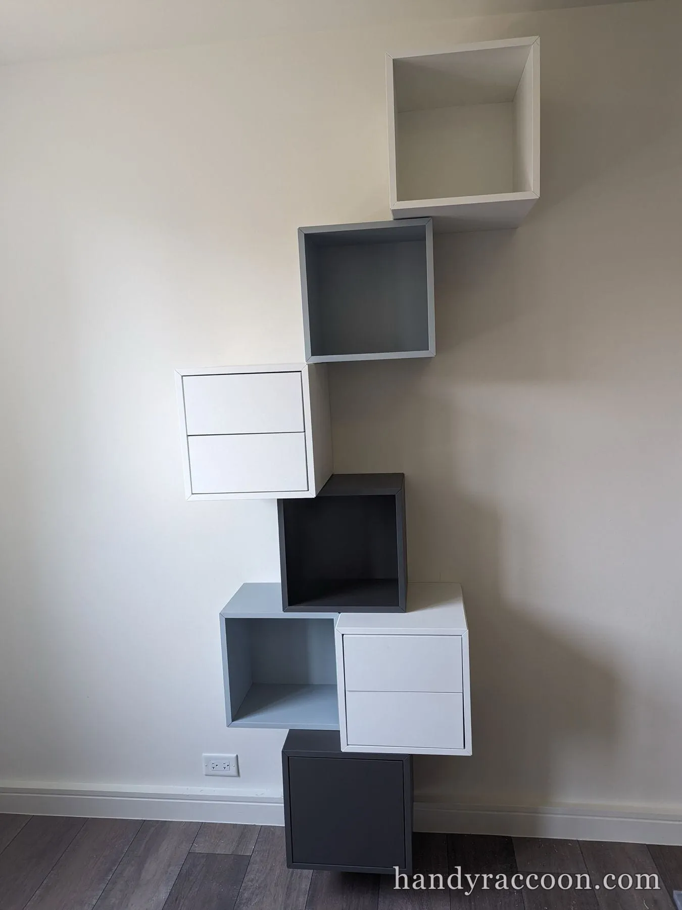 White and gray modular cube shelves mounted on a wall in a staggered pattern.