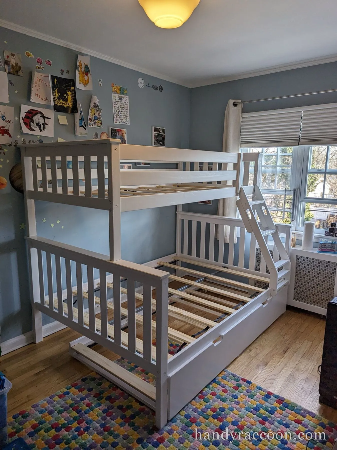 White and gray twin over full bunk bed with ladder and pull-out trundle, slats visible, no mattresses.