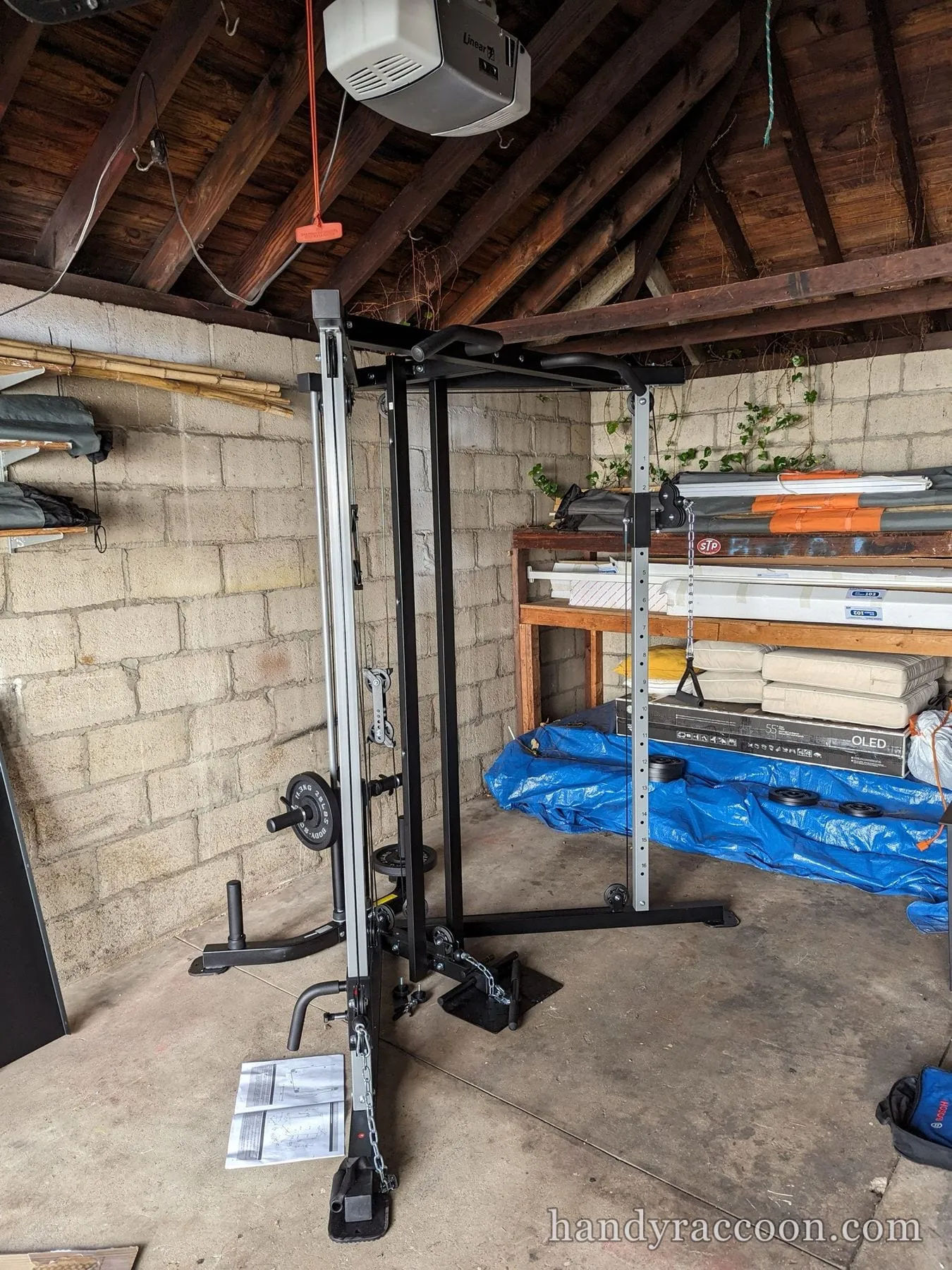 Functional trainer cable crossover machine standing in a cluttered garage.