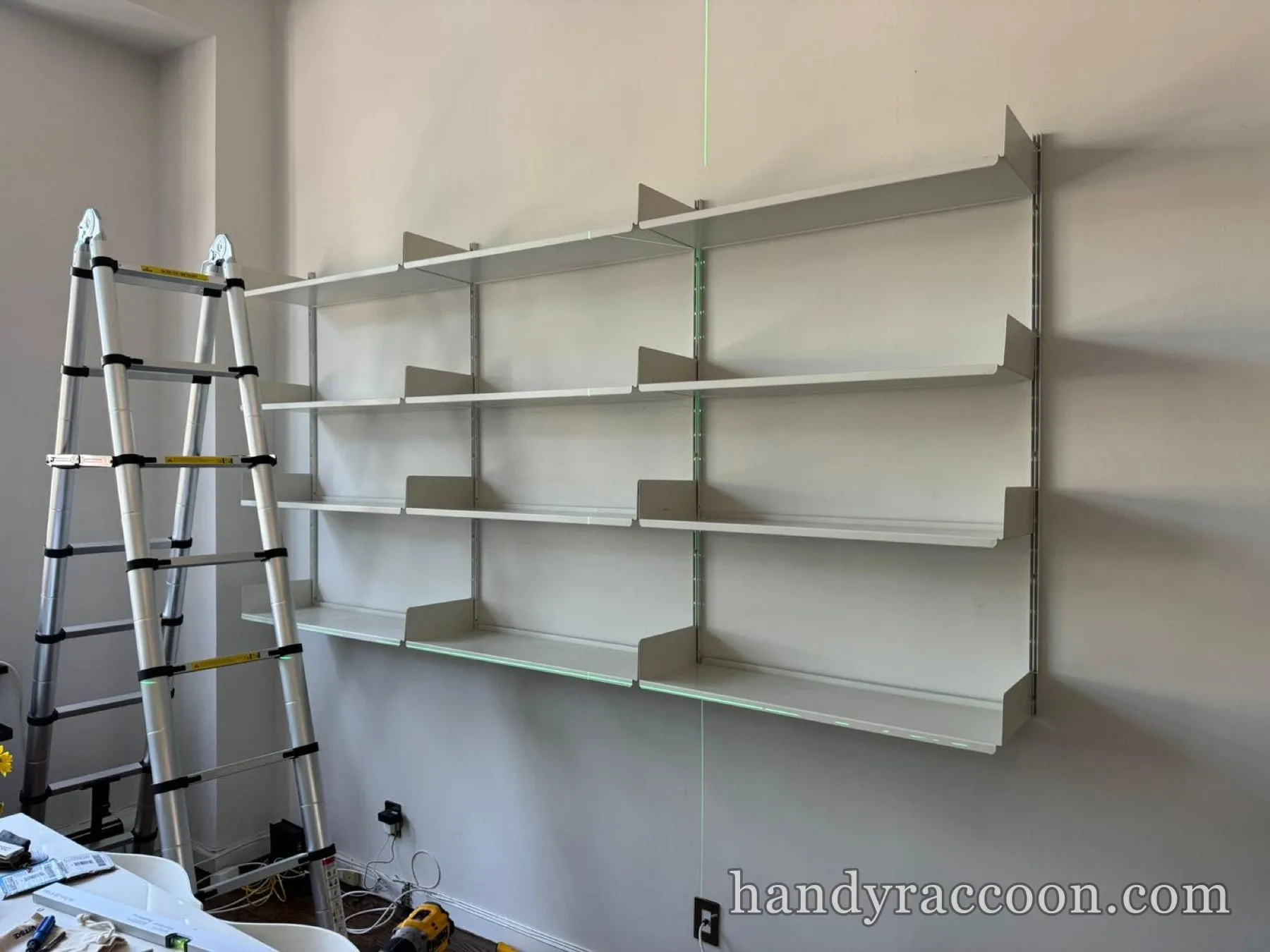 White wall-mounted closet shelving columns installed in a New York apartment next to a folding ladder.