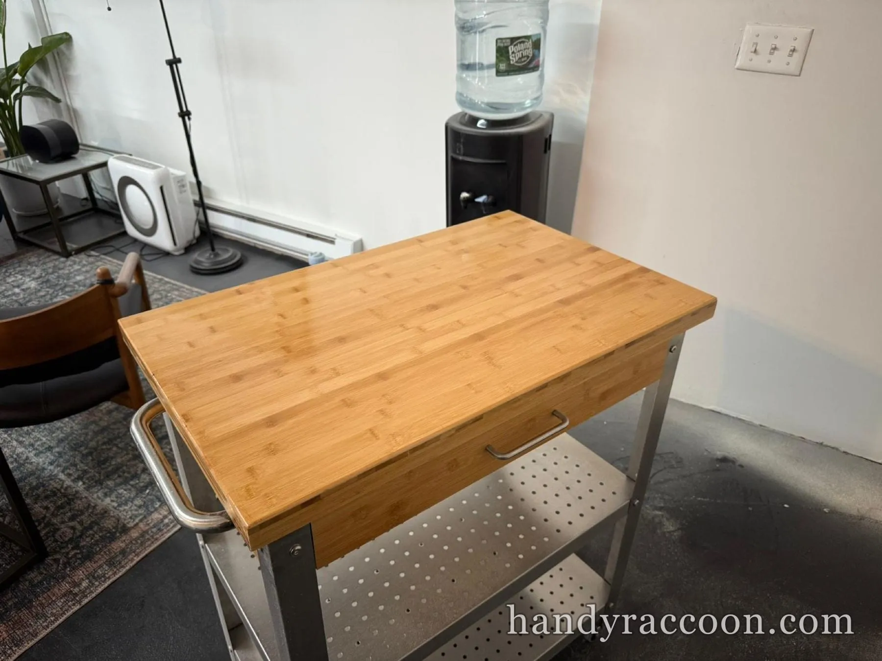 Clean sanded wood butcher-block top on a stainless rolling cart in a room with a water cooler.