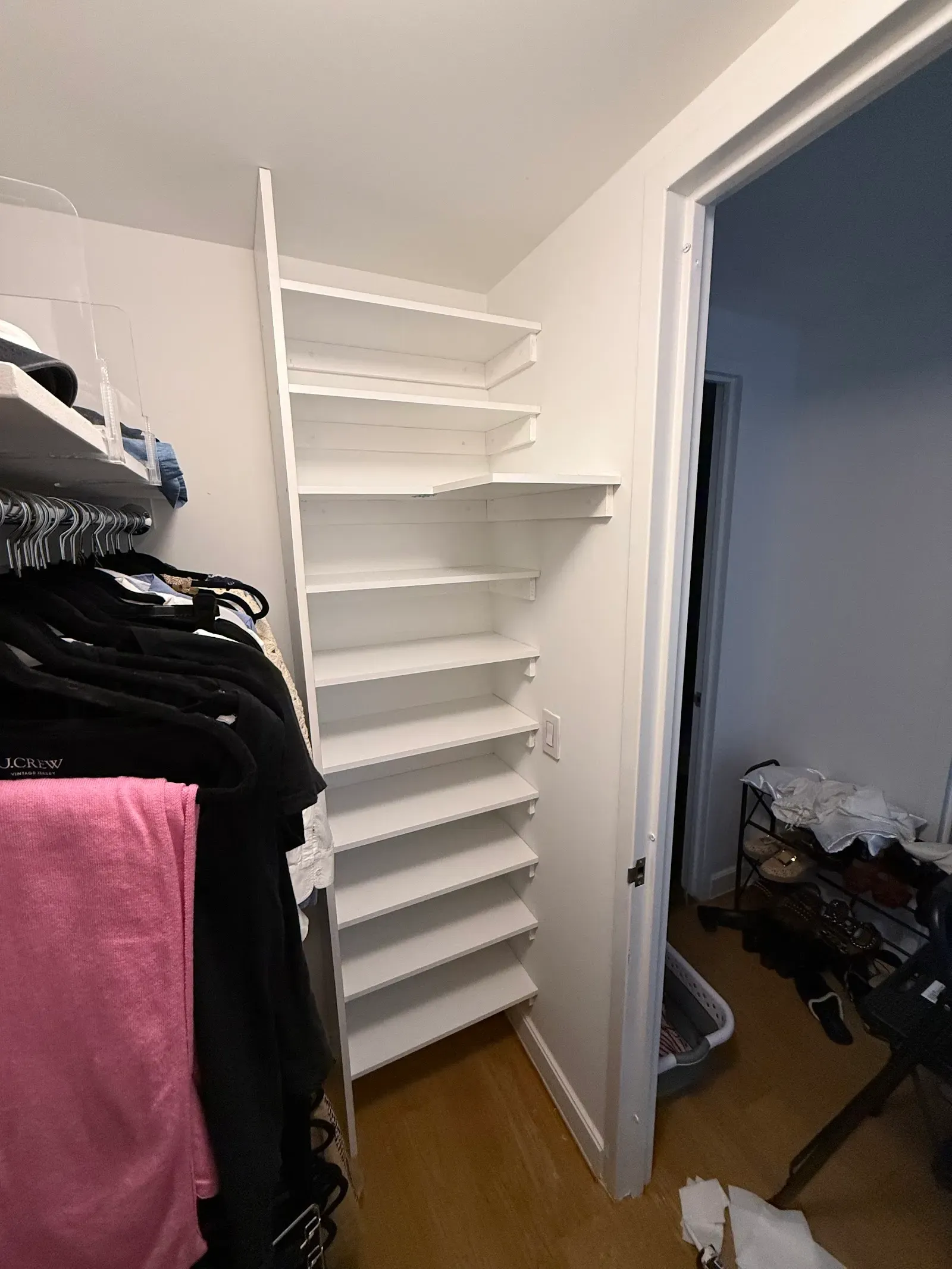 Custom white corner shelving built into a walk-in closet