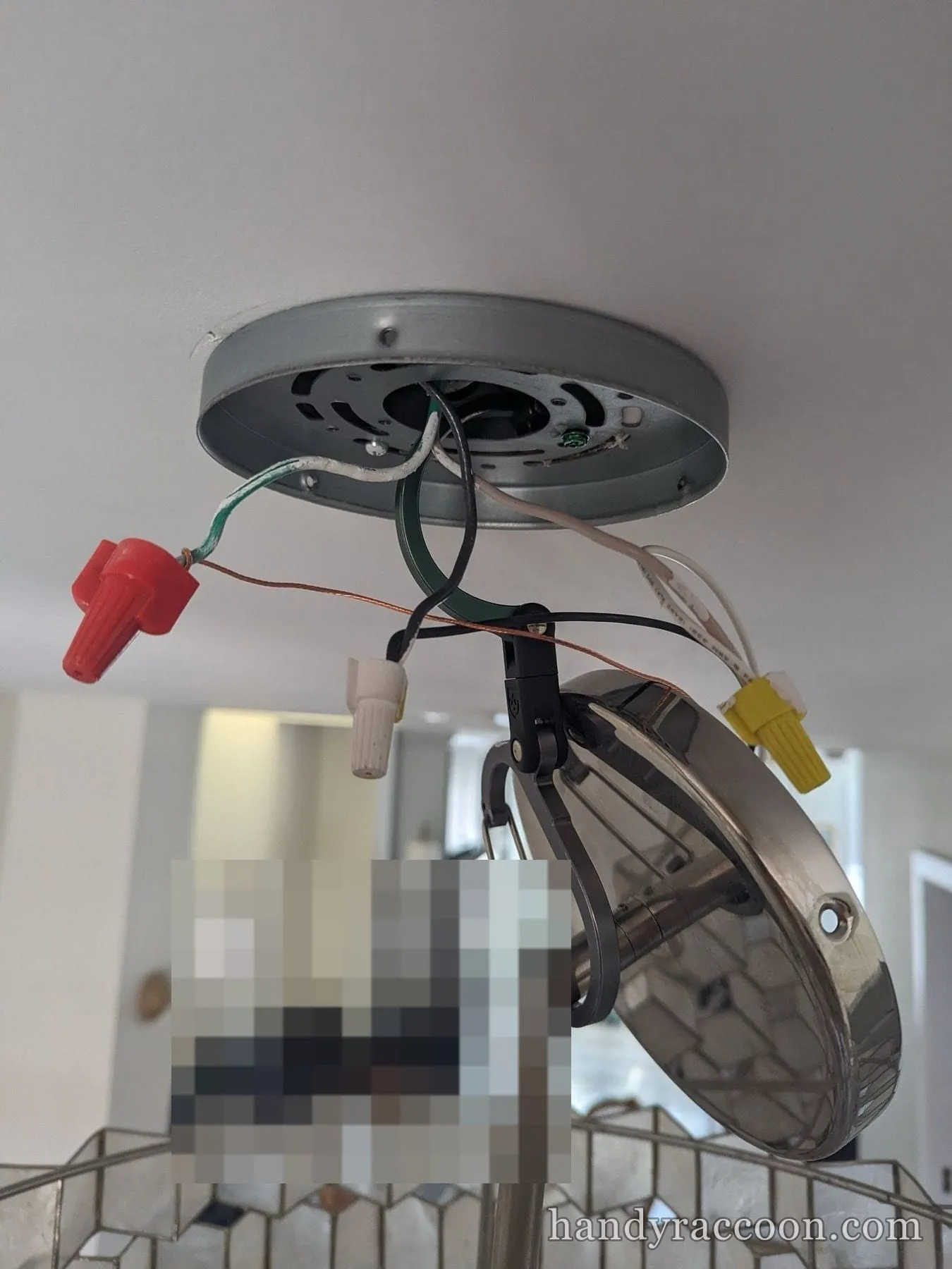 Glass pendant canopy held to a ceiling box with red, white, and yellow wire nuts and exposed wiring.