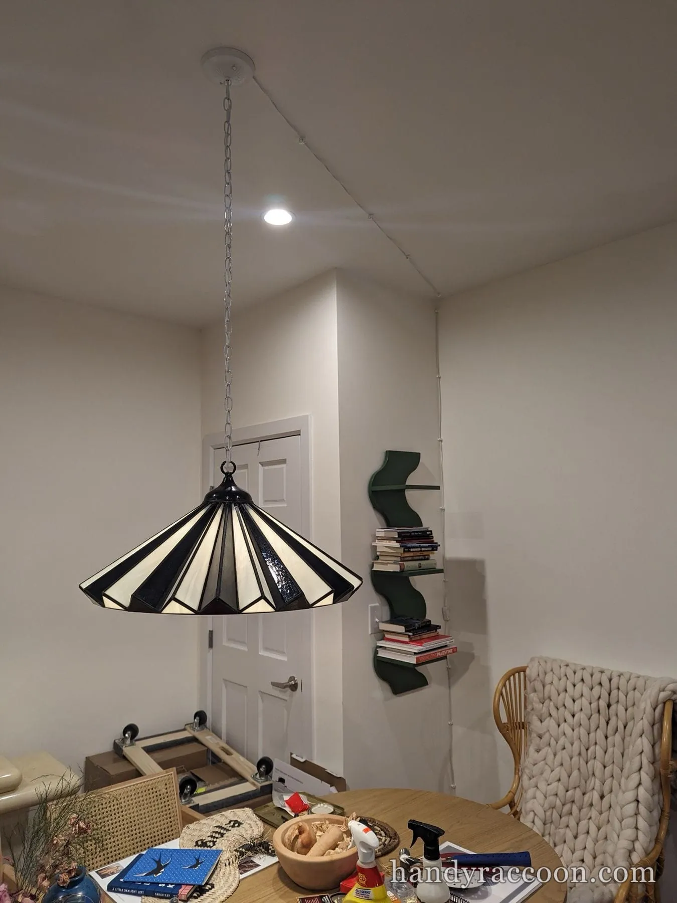 Black and white stained glass pendant lamp hanging by a chain over a dining area.