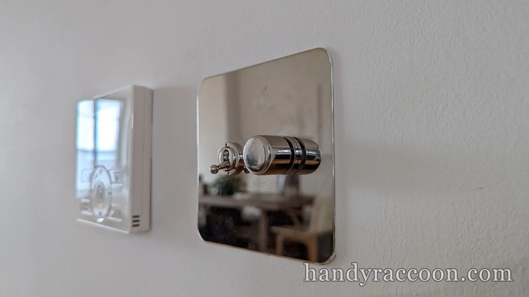 Shiny nickel dimmer switch with a metal plate mounted on a white wall.