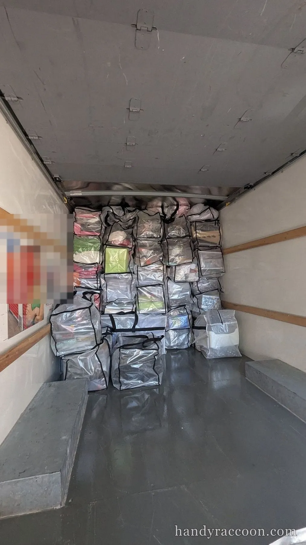 Interior of a box truck loaded with clear plastic storage bags stacked and strapped along the wall.