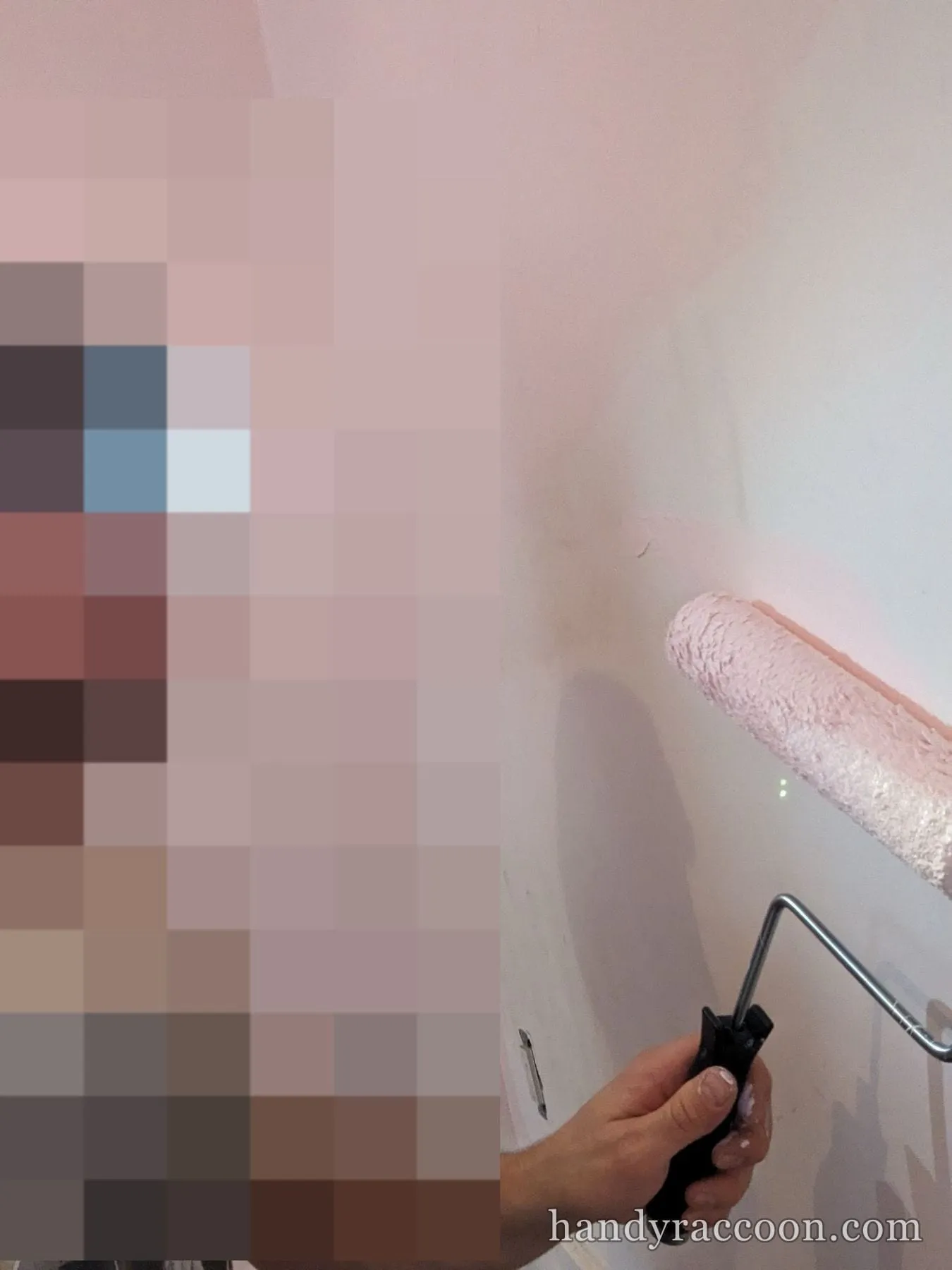 Man using a paint roller on an interior wall while wearing a headlamp.