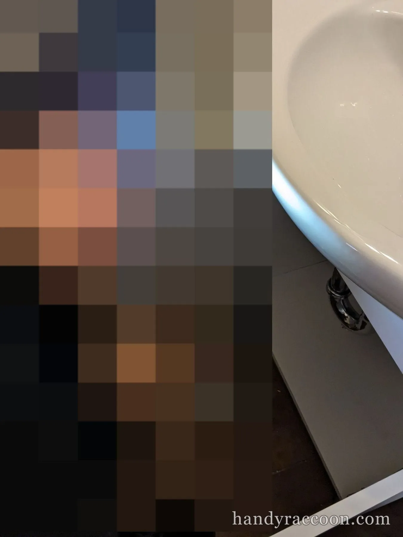 Bearded worker wearing a headlamp reaching under a bathroom fixture, tools on the floor.