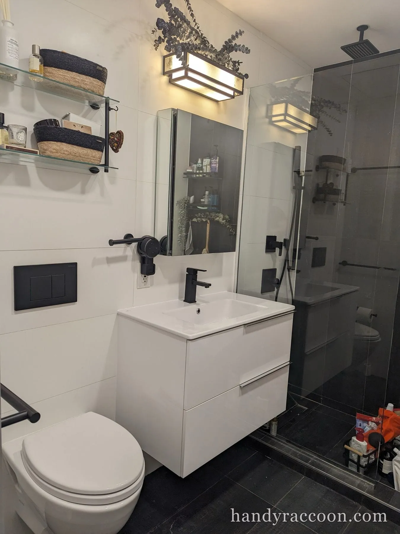 Finished white gloss floating vanity with black faucet, mirror cabinet, and glass shower in a bath.