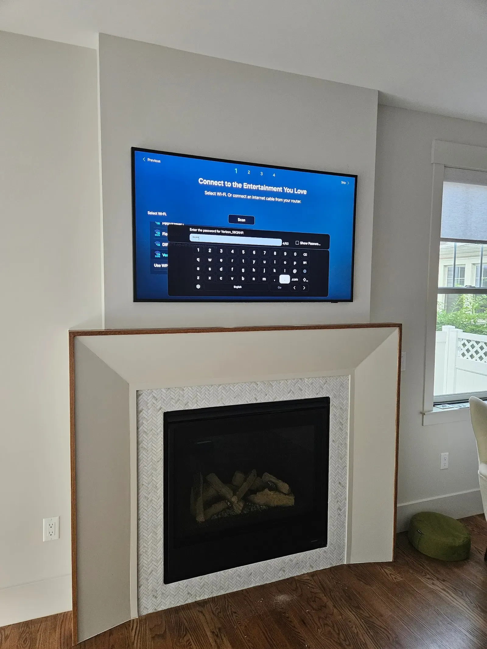 Television mounted flush above a tiled fireplace in a Brooklyn living room